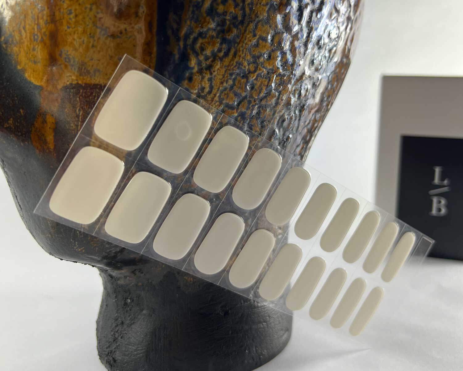 stone off white semi-cured gel nails in mockup to show product against textured brown ceramic head with la-bek uv lamp in the background