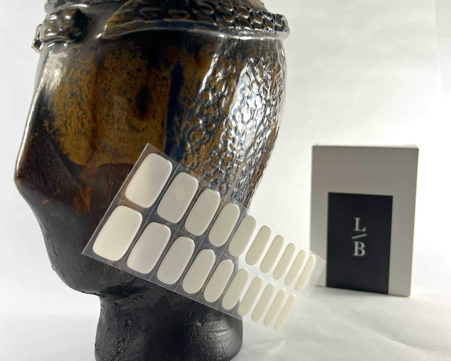 stone off white semi-cured gel nails in mockup to show product against textured brown ceramic head with la-bek uv lamp in the background