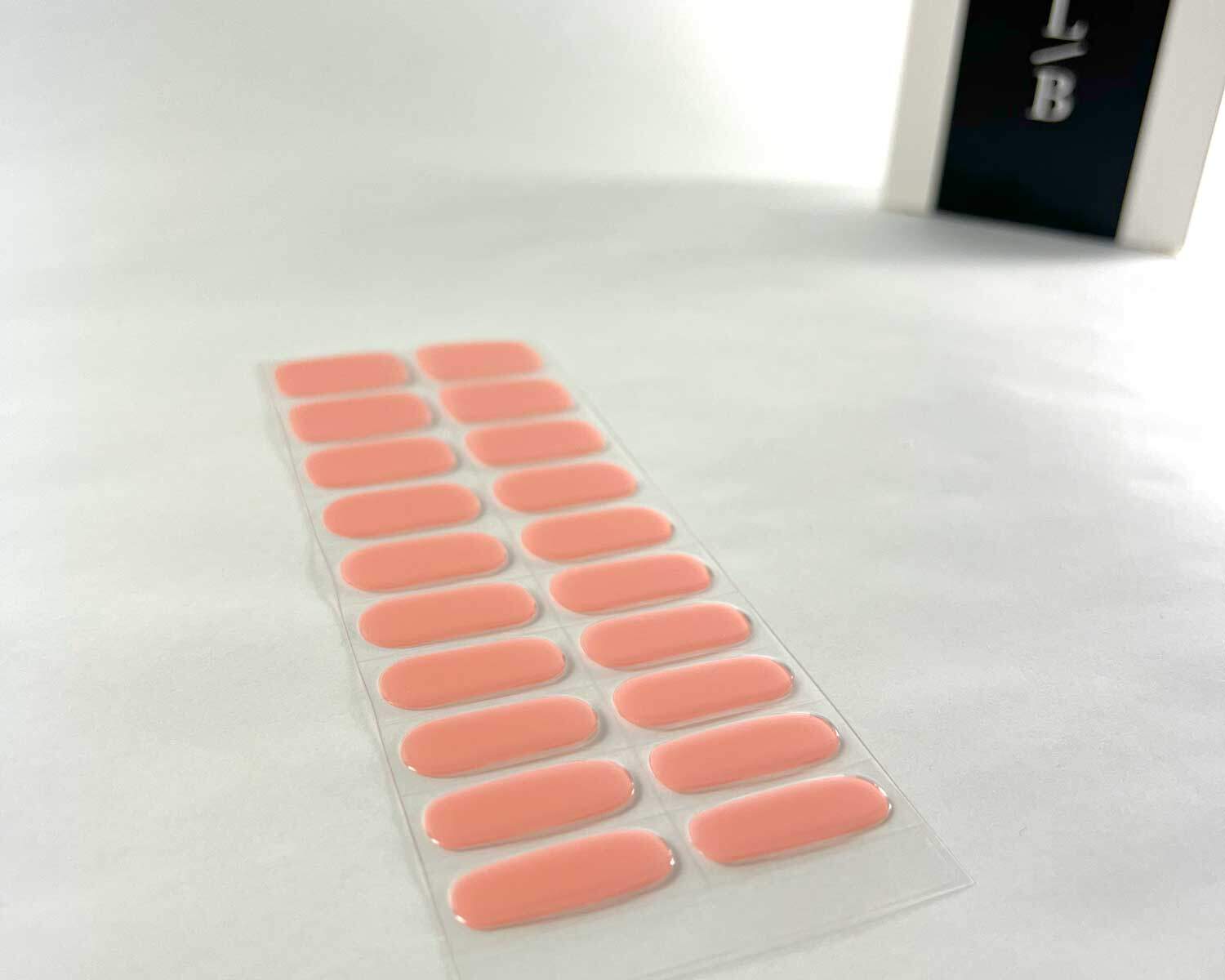 Strawberry Sunday pink semi-cured gel nails on angle zoomed in on white background with la-bek uv lamp box in the background