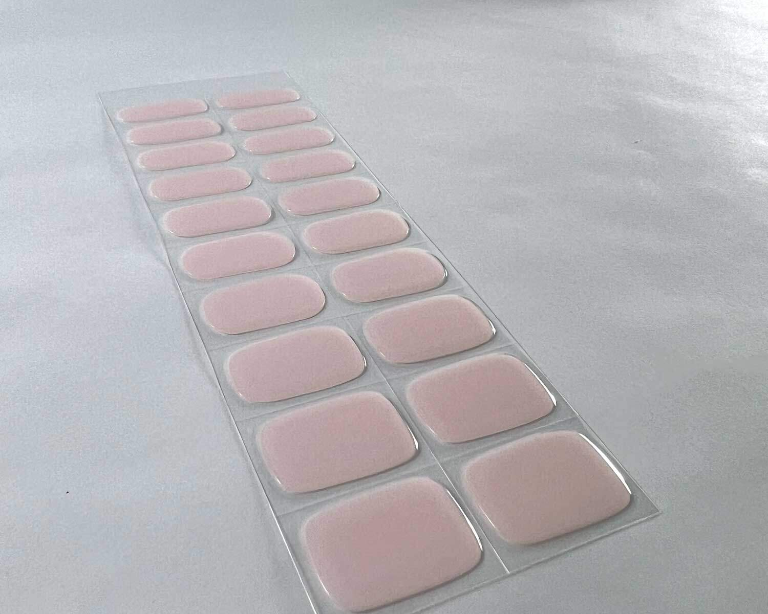 Soft pink semi-cured gel nails on angle zoomed in on white background