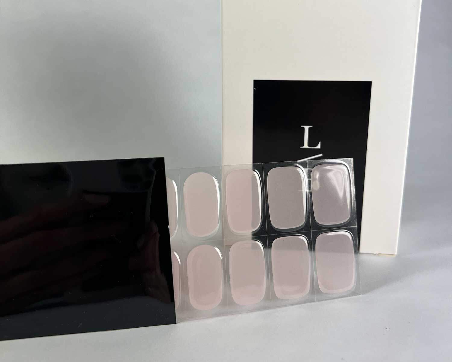 Soft pink semi-cured gel nails in black light sensitive strip with la-bek uv lamp box in the background