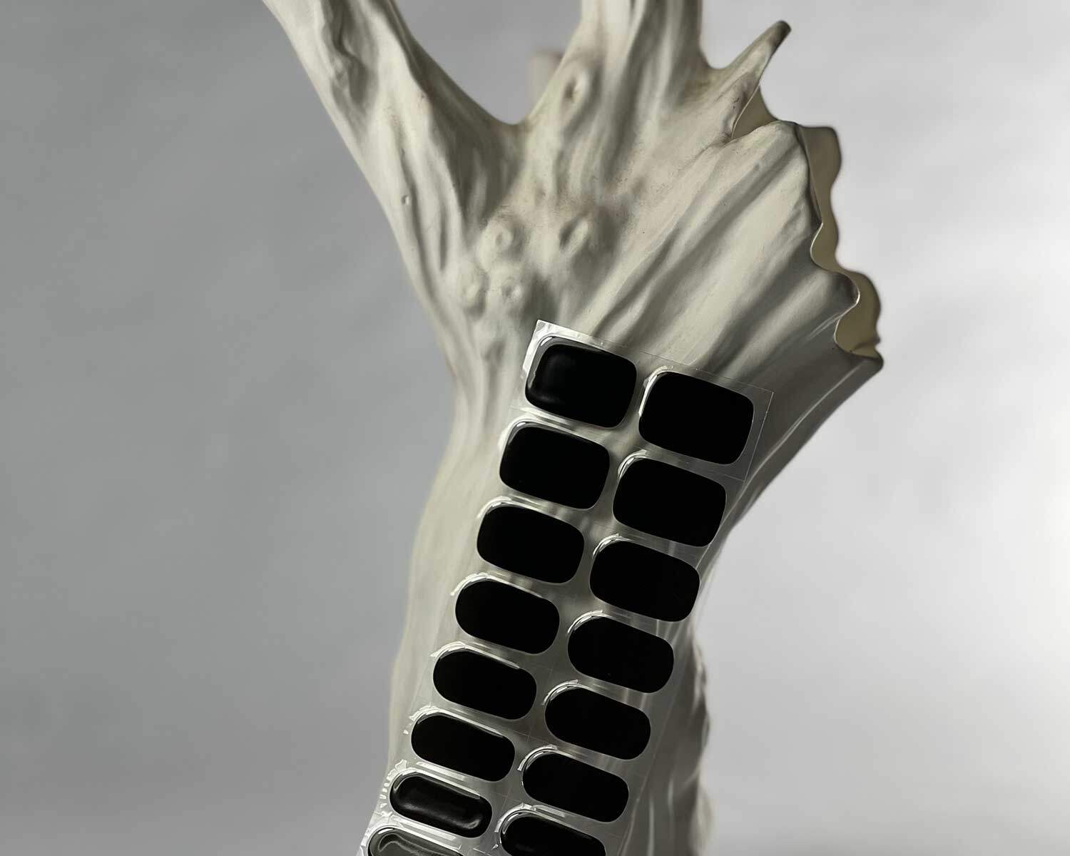 Night black semi-cured gel nails in mockup to show product against white textured tree with la-bek uv lamp in the background