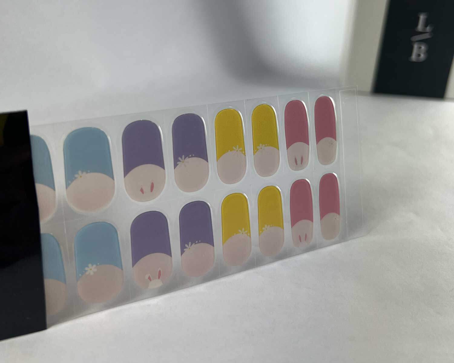 French bunny rainbow semi-cured gel nails in black light sensitive strip with la-bek uv lamp box in the background