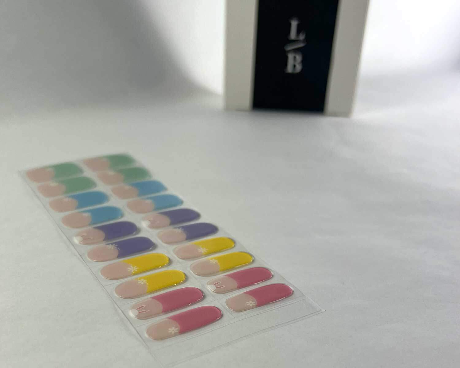 French bunny rainbow semi-cured gel nails on angle zoomed in on white background with la-bek uv lamp box in the background