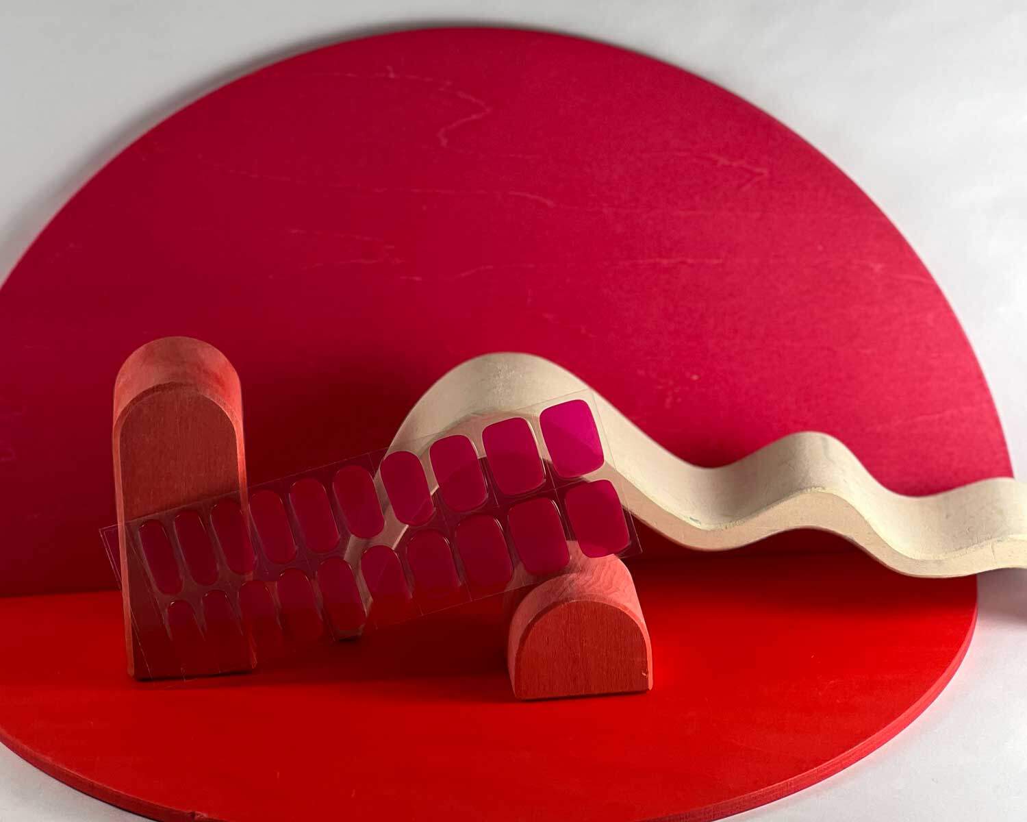 Lipstick love pink semi-cured gel nails in mockup to show product against red wooden blocks with la-bek uv lamp in the background