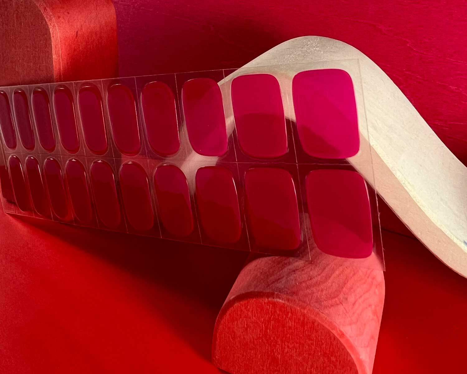Lipstick love pink semi-cured gel nails zoomed in angle mockup to show product against red wooden blocks with la-bek uv lamp in the background