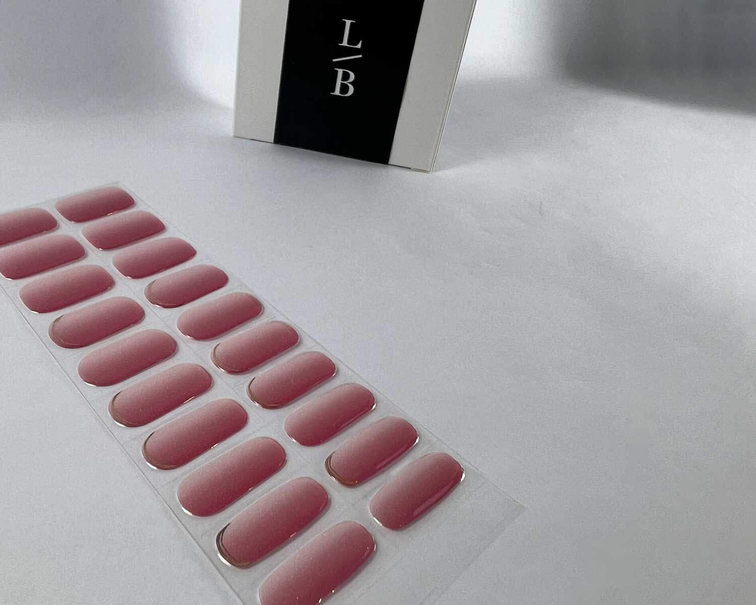 Golden sunset pink semi-cured gel nails on angle zoomed in on white background with la-bek uv lamp box in the background