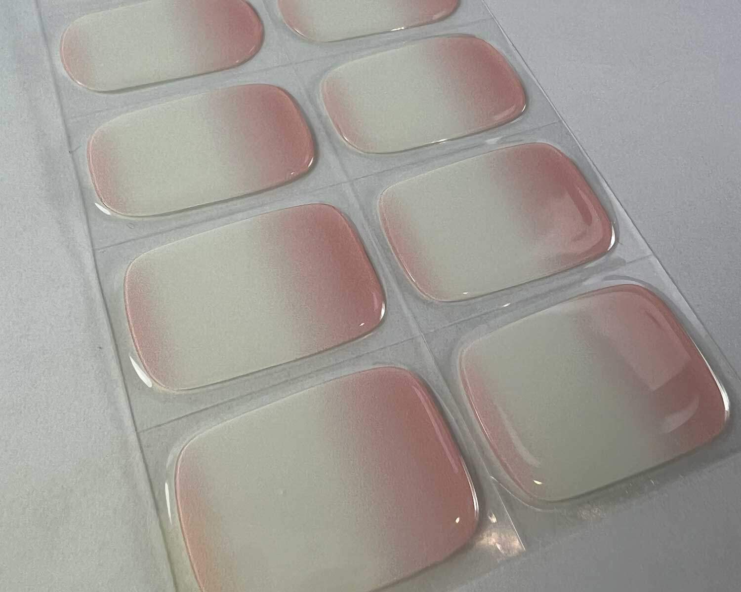 Ombre pink semi-cured gel nails on angle zoomed in on white background