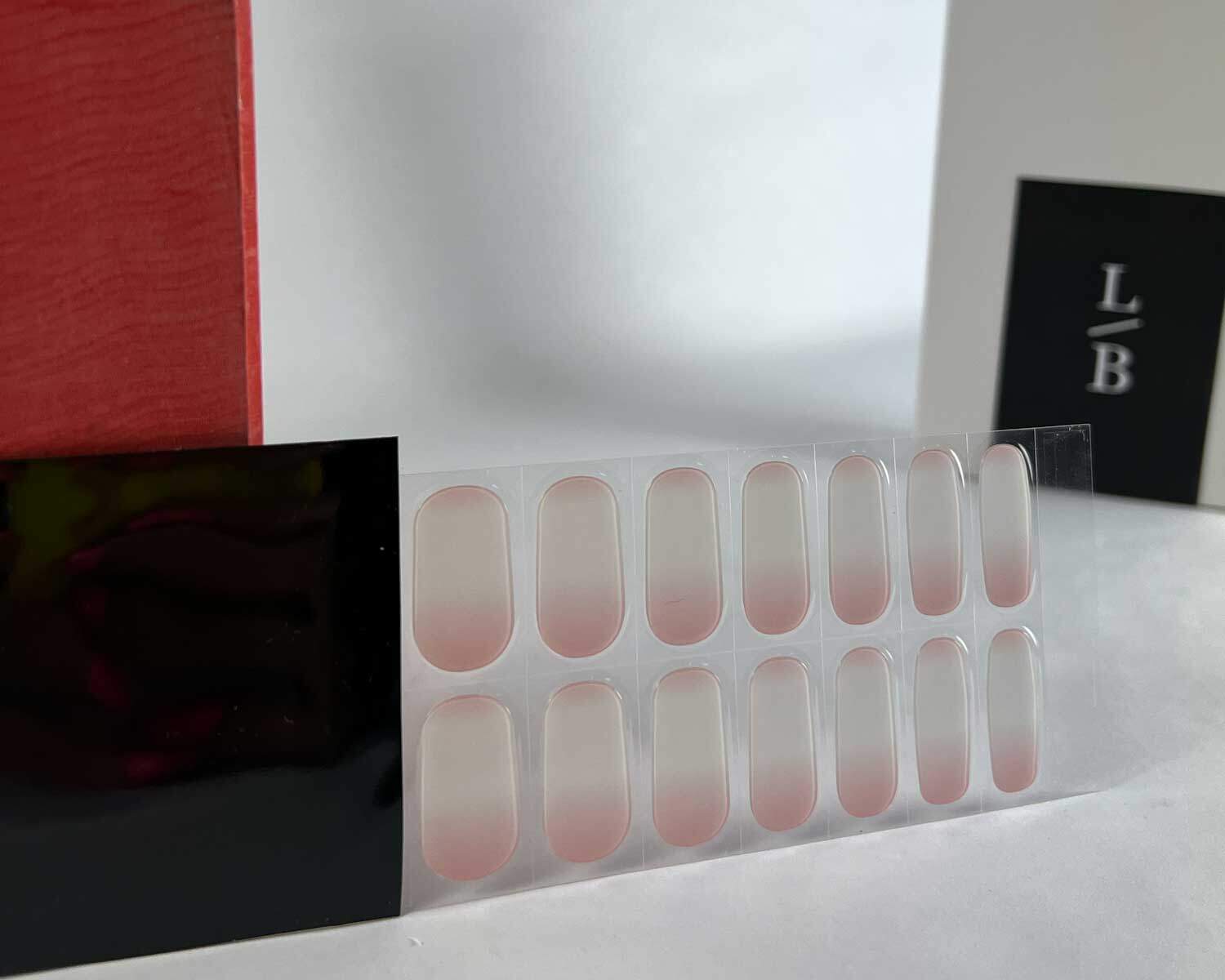 Ombre pink semi-cured gel nails in black light sensitive strip with la-bek uv lamp box in the background