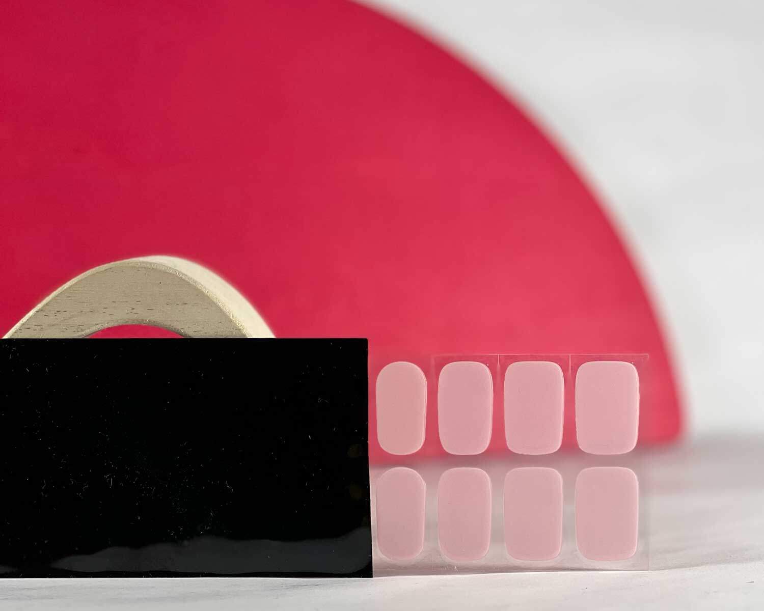 Pale pink power semi-cured gel nails in black light sensitive strip with la-bek uv lamp box in the background