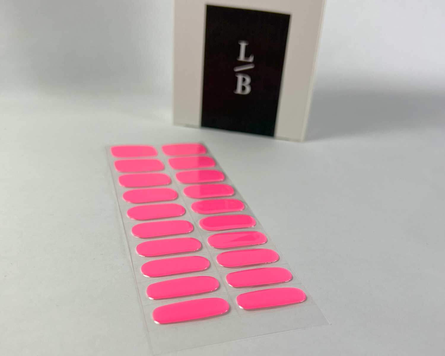 Barbie pink semi-cured gel nails on angle zoomed in on white background with la-bek uv lamp box in the background