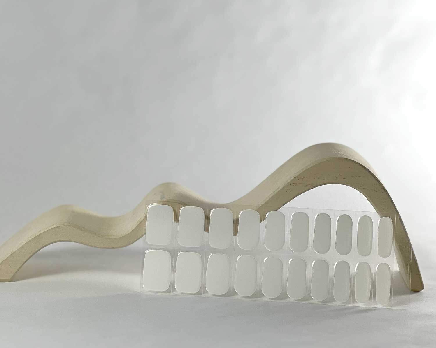 pure-white-semi-cured-nails-bag-curve Pure White semi-cured gel nails in mockup to show product against white wave wooden block