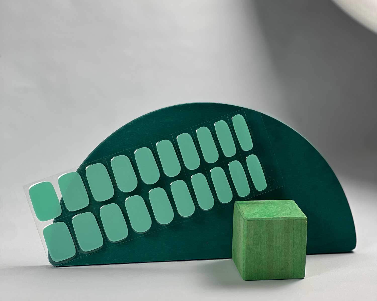 Aqua semi-cured gel nails in mockup to show product against green wooden blocks