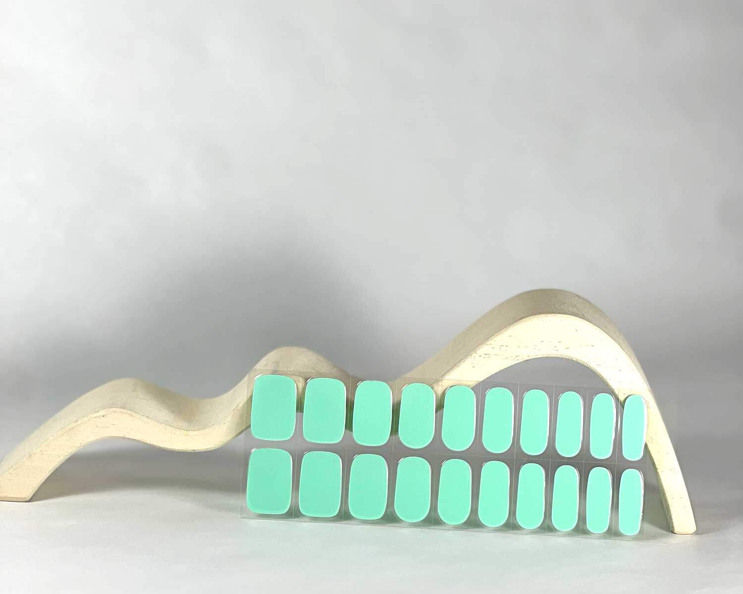 Aqua semi-cured gel nails in mockup to show product against white wave wooden block