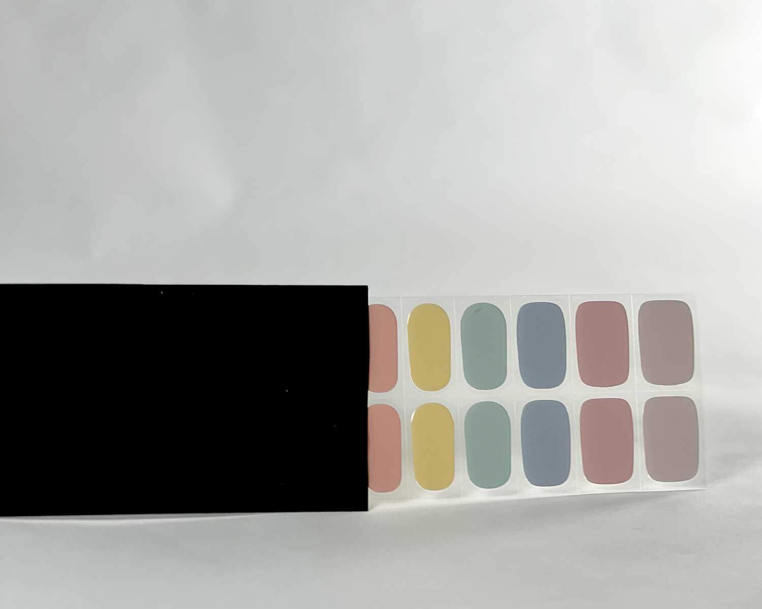 Candy bar rainbow semi-cured gel nails in black light sensitive strip with la-bek uv lamp box in the background