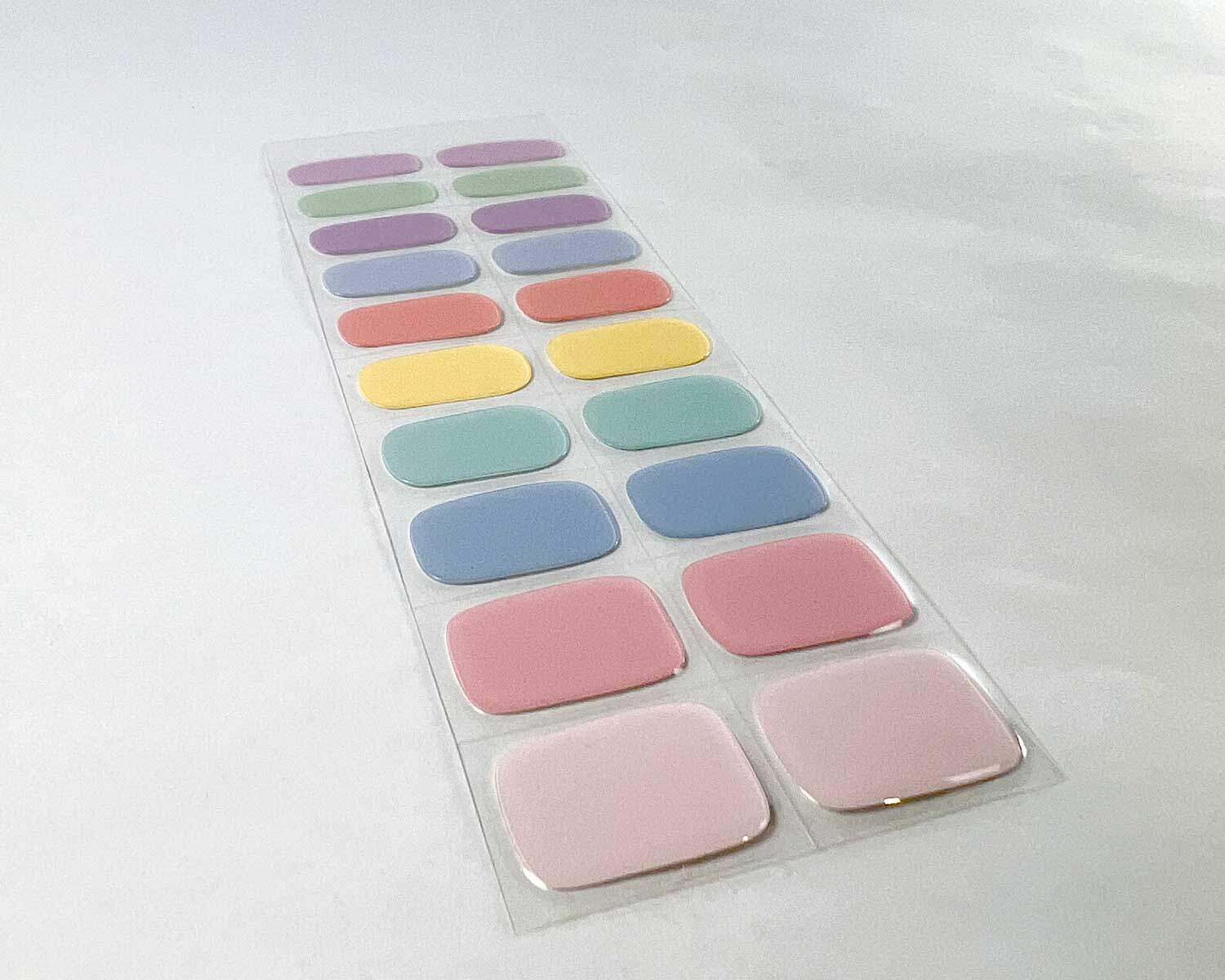 Candy bar rainbow semi-cured gel nails on angle zoomed in on white background