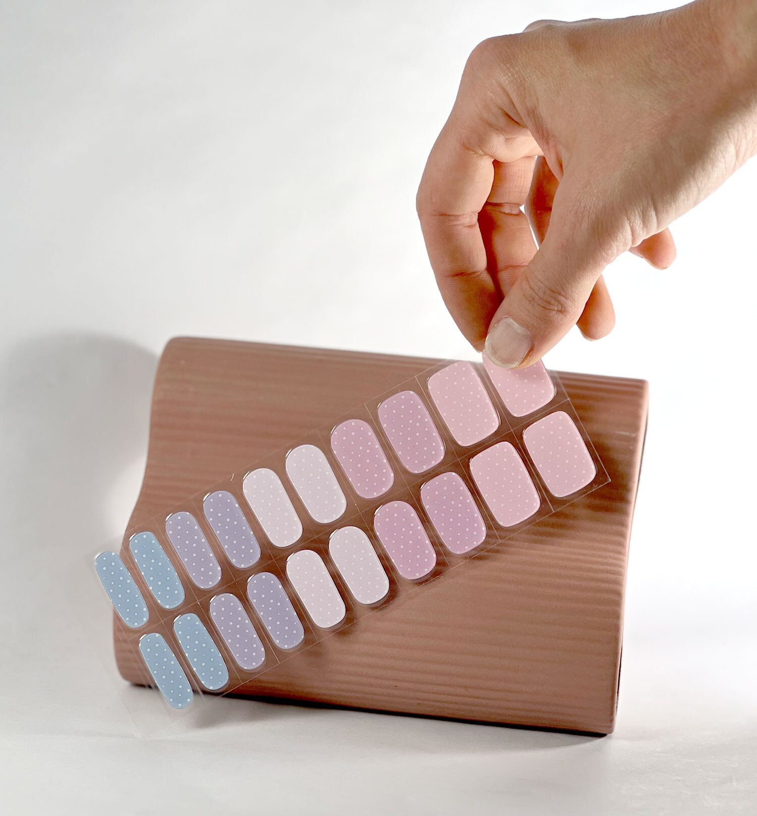 Pastel Polka Dots semi-cured gel nails in mockup to show product against pink vase with hand holding strip
