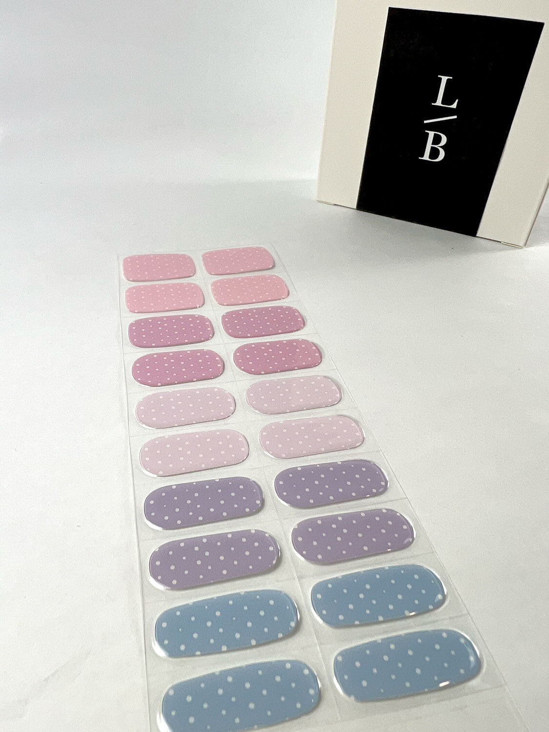 Pastel Polka Dots semi-cured gel nails on angle zoomed in on white background with la-bek uv lamp box in the background