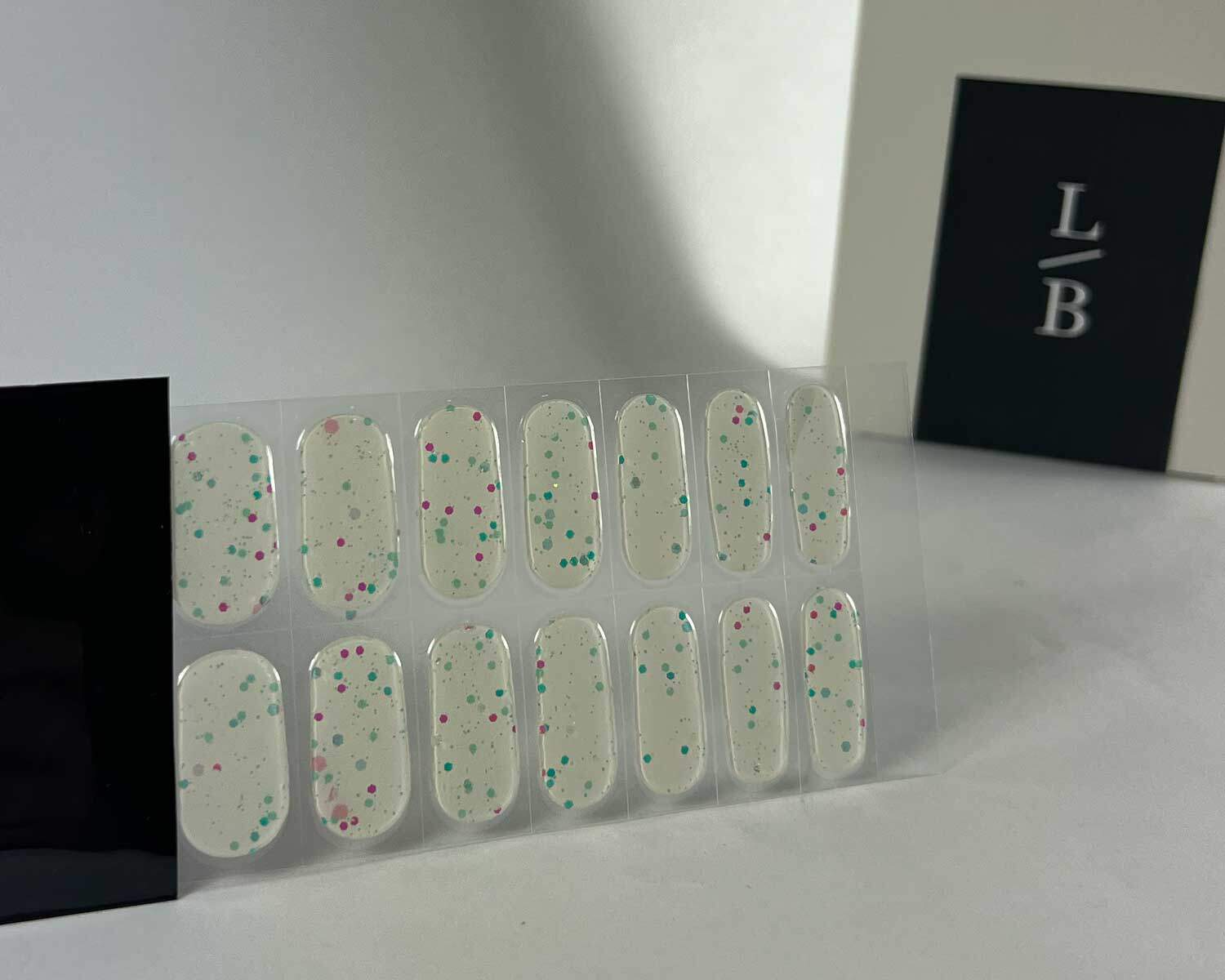 Sprinkle-Glow-Snow-semi-cured-gel-nail-black-strip Sprinkle snow Glow in the dark white semi-cured gel nails in black light sensitive strip with la-bek uv lamp box in the background