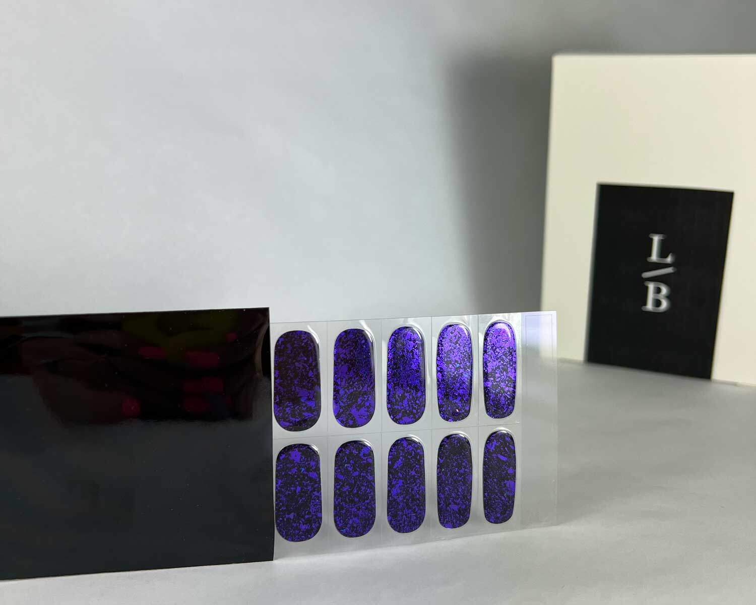 Violet Luster black and purple semi-cured gel nails in black light sensitive strip with la-bek uv lamp box in the background