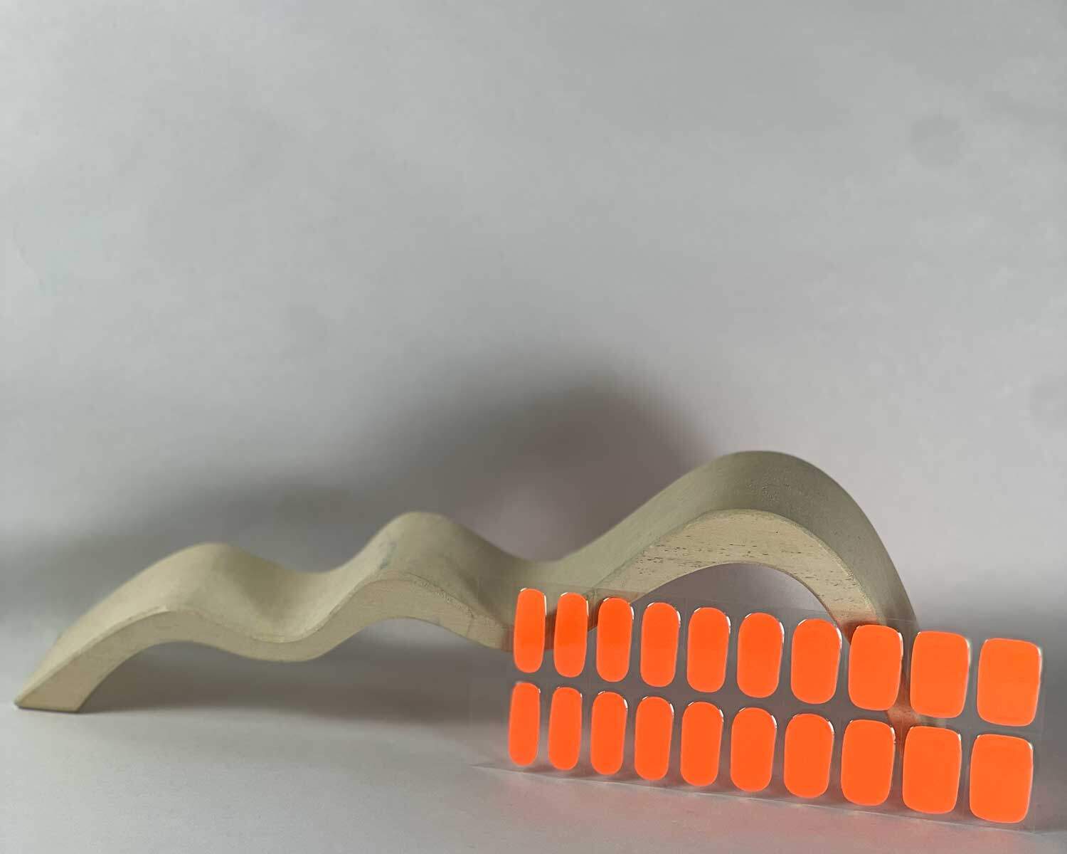 Neon Orange Glow in the dark semi-cured gel nails in mockup to show product against white curved wooden block