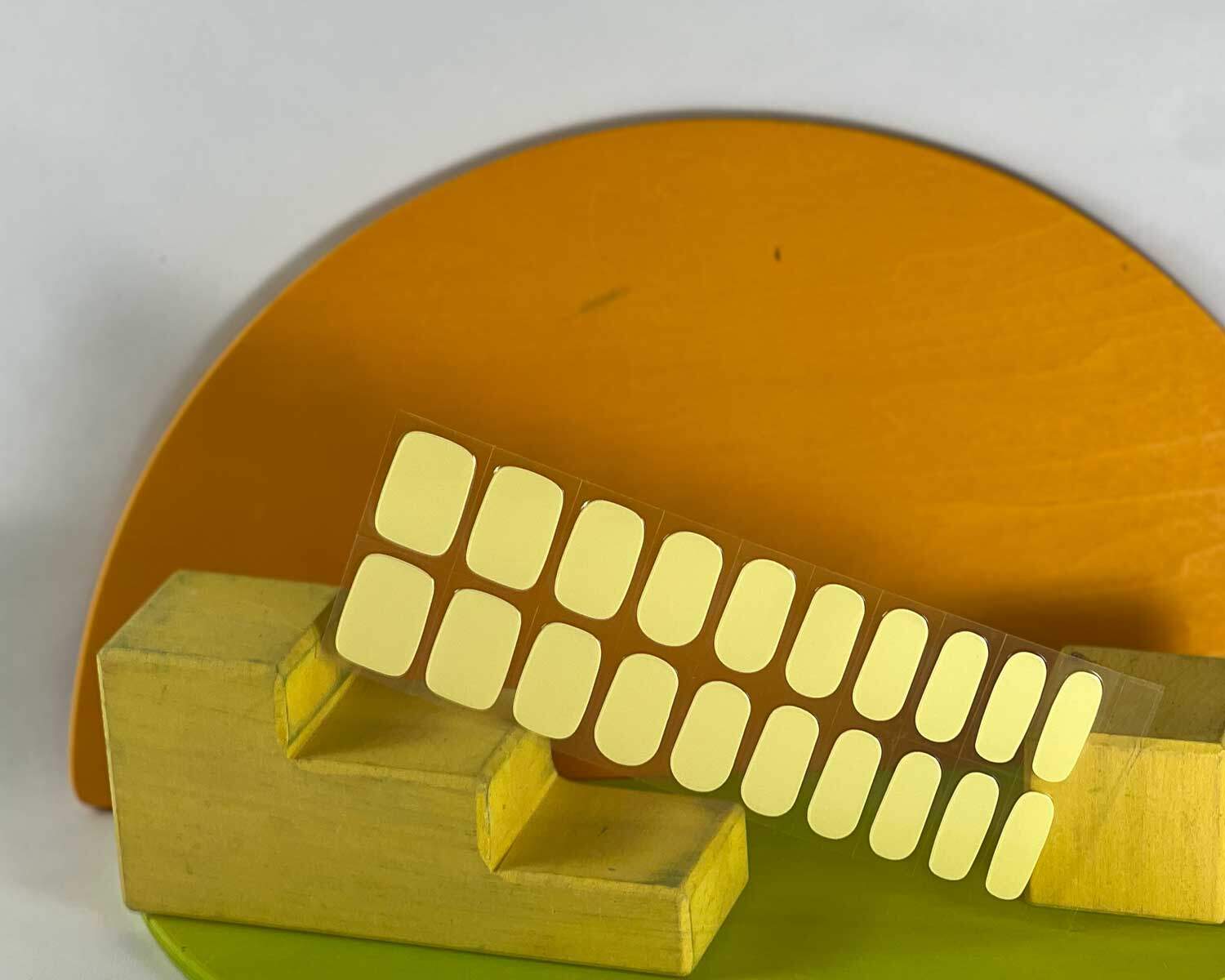 Lemonade yellow semi-cured gel nails in mockup to show product against green, orange and yellow wooden blocks