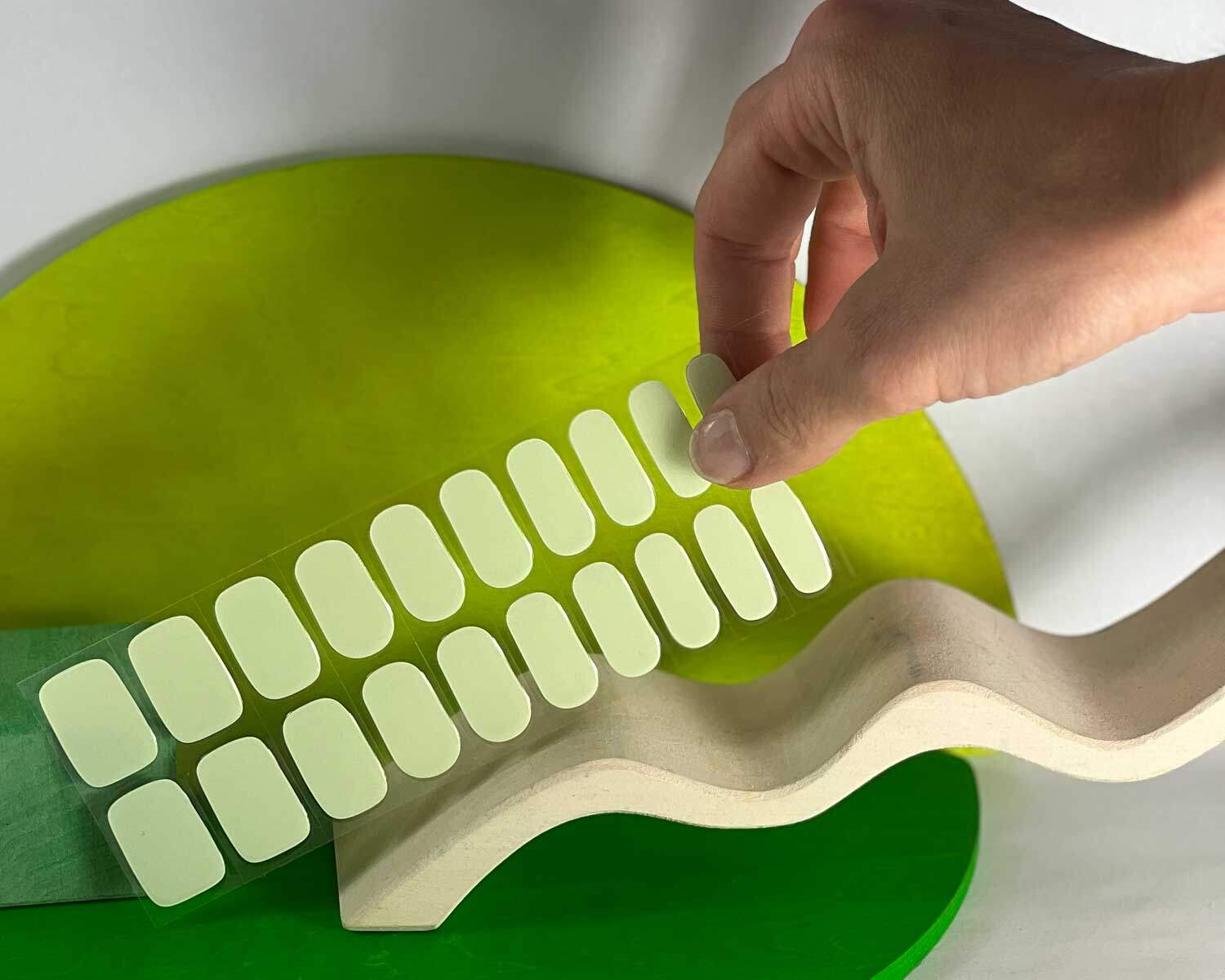 Pistachio green semi-cured gel nails in mockup to show product against white and green wooden blocks