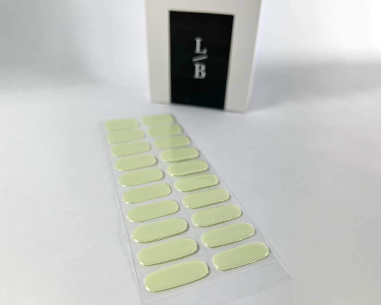 Pistachio green semi-cured gel nails on angle zoomed in on white background with la-bek uv lamp box in the background