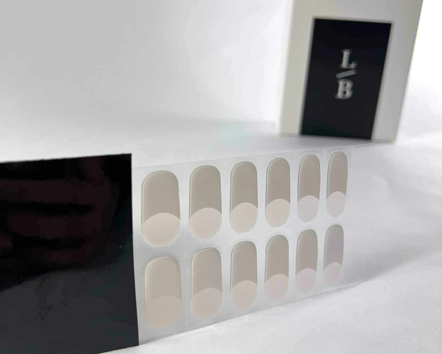 classic french semi cured gel nails in black light sensitive strip with la-bek uv lamp box in the background