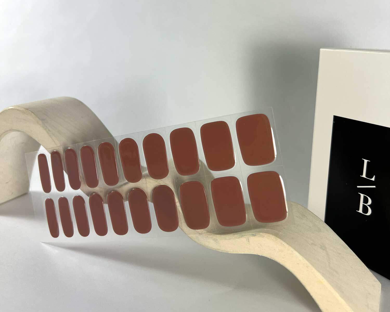 mocha brown semi-cured gel nails in mockup to show product against wave style wooden white block with la-bek uv lamp in the background
