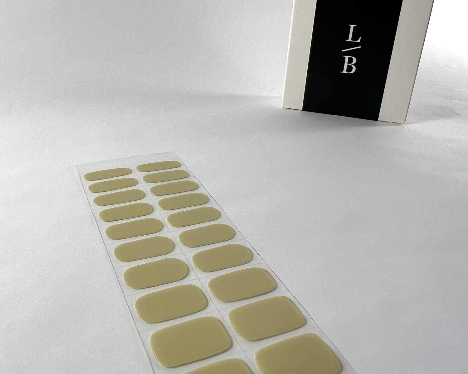 artichoke green semi cured gel nails on angle zoomed in on white background with la-bek uv lamp box in the background