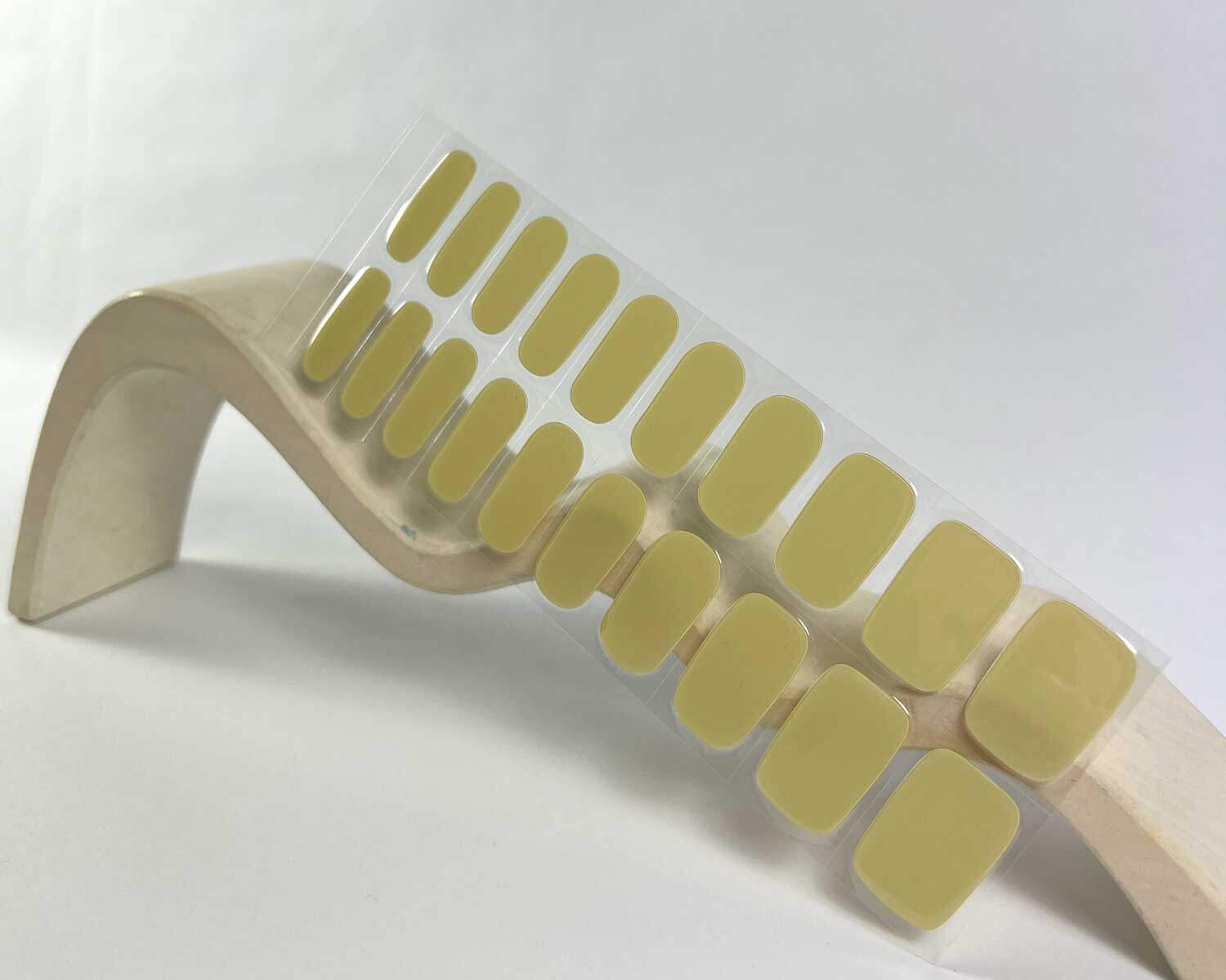 artichoke green semi-cured gel nails in mockup to show product against white wave wooden block