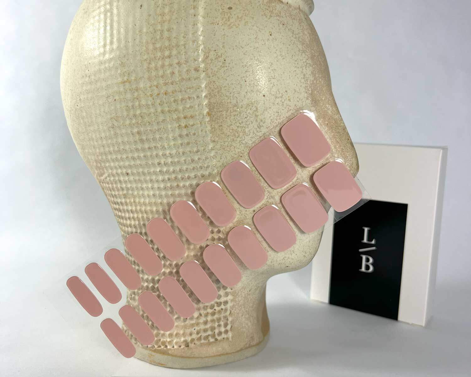 pink marshmallow semi-cured gel nails in mockup to show product against textured ceramic head with la-bek uv lamp in the background